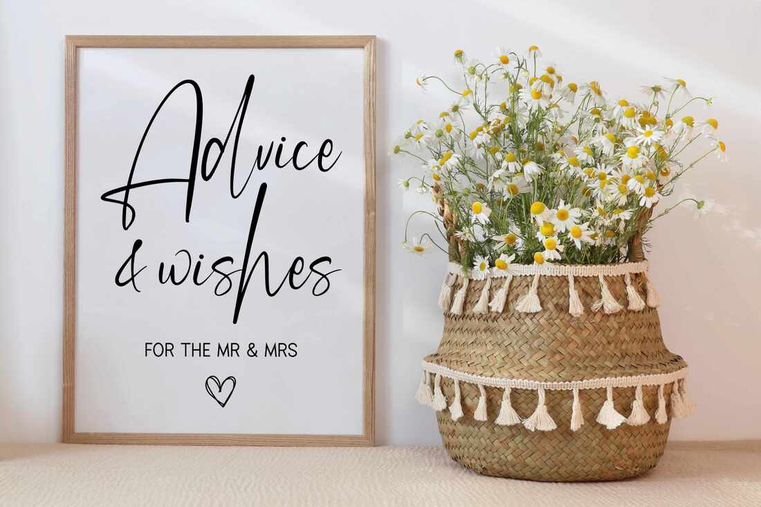 Advice & Wishes for the Mr and Mrs Sign. It is framed and sitting on a table next to a basket of white flowers