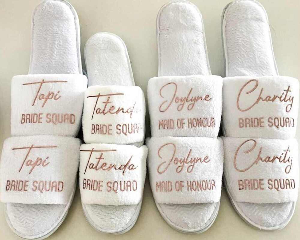 White slippers personalised with people's names and the term 'bride squad'