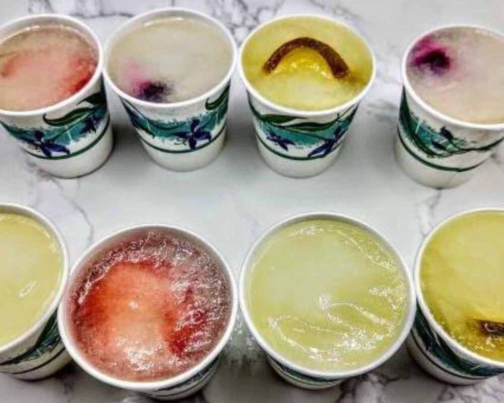 Frozen cocktails in small cups. There are eight of them sitting on a marble bench