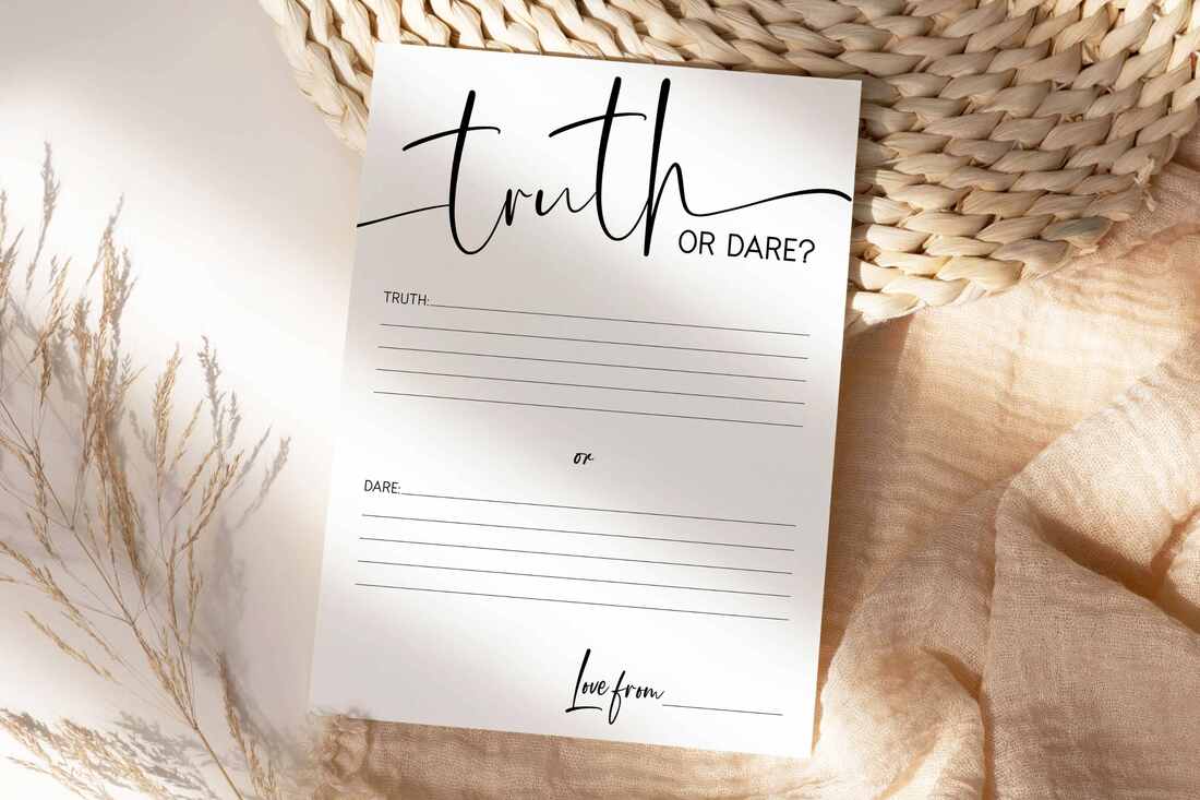Printable Truth or Dare Game Cards with a minimalist design. The game card is lying on top of a blush table runner and natural placemat.