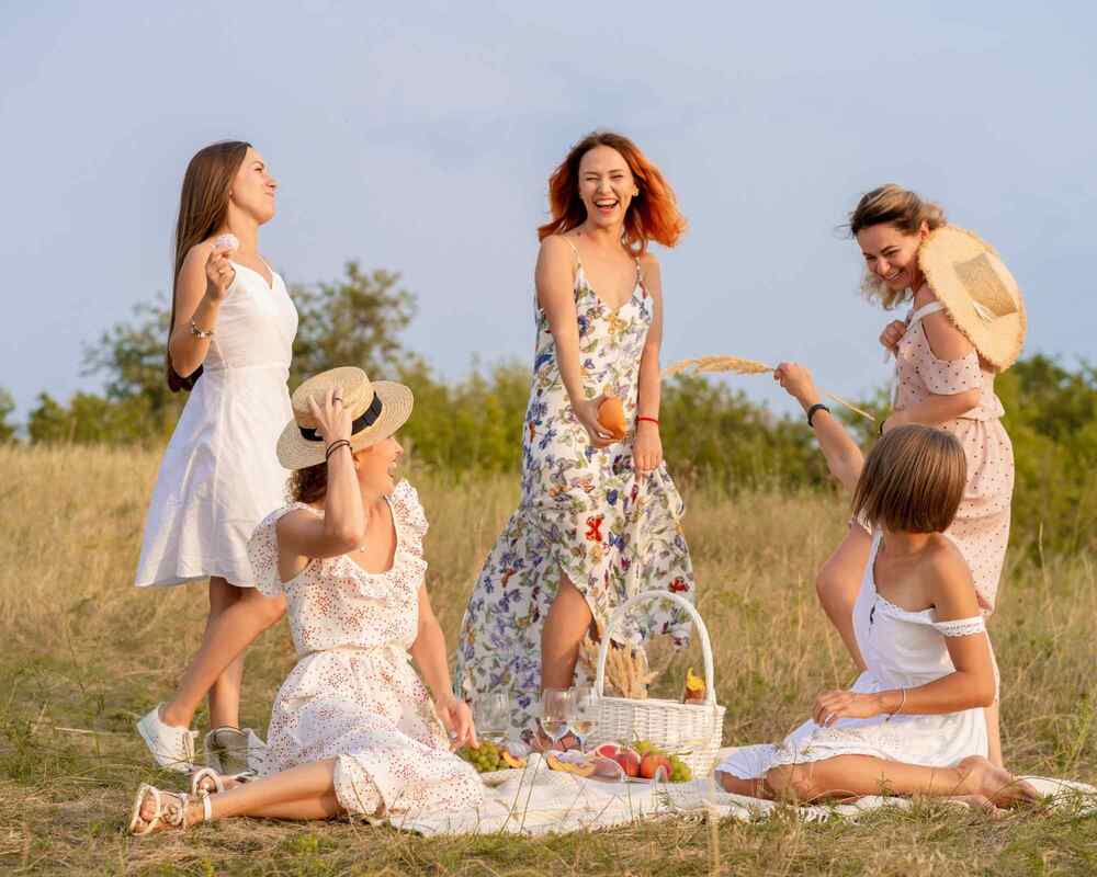 Picnic bachelorette party where five women are picnicking in a grassy area, all happy and smiling