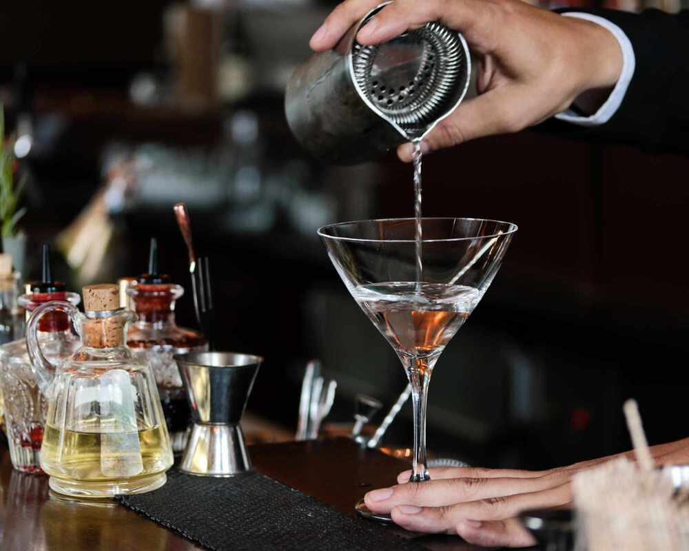 A bar tender making martinis in a bar