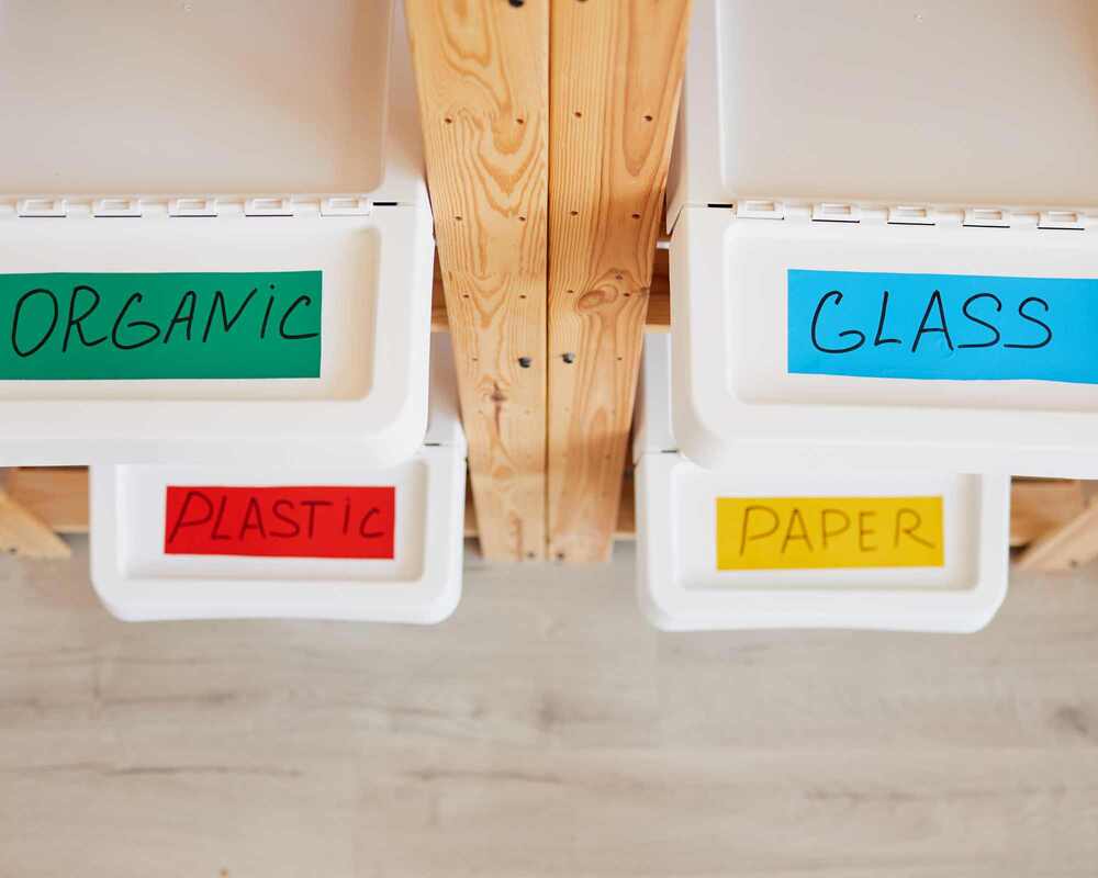 Four white bins, each with a different label: organic, glass, plastic, paper
