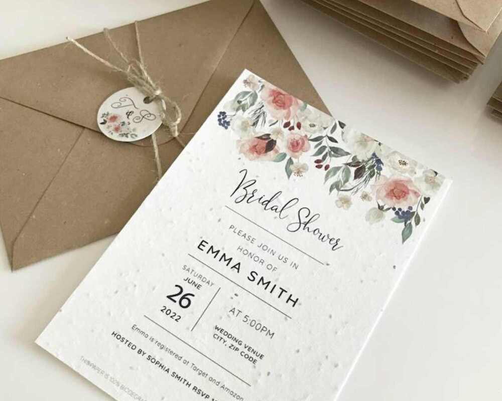 Bridal shower invitation featuring pink and white flowers. The invite is on a table next to a brown envelope