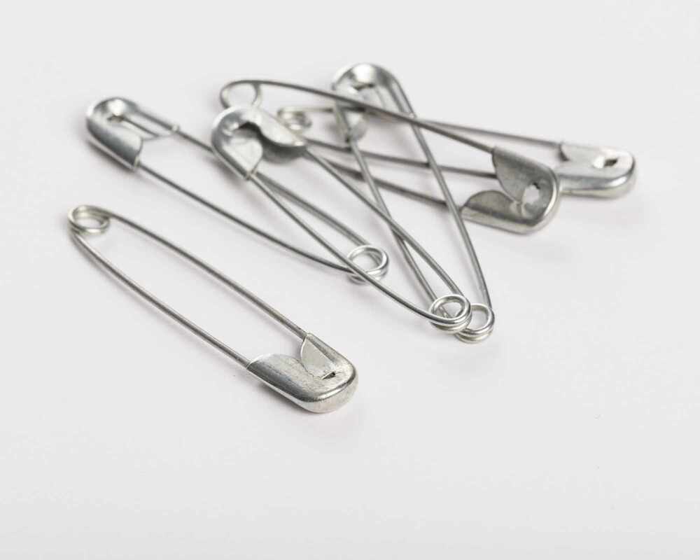 Silver safety pins on a grey backdrop